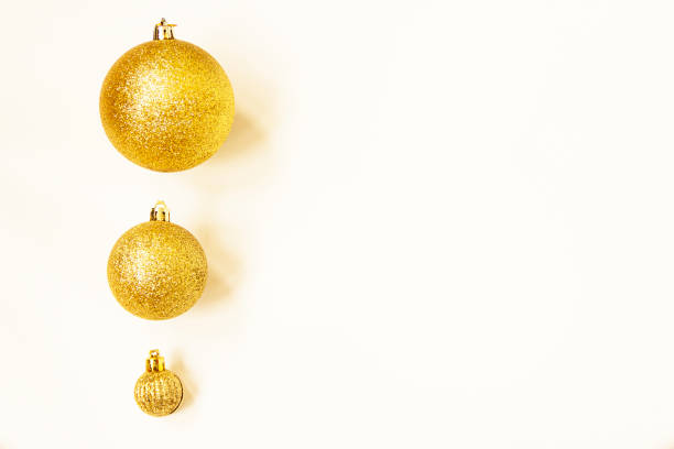 istock Three golden Christmas balls of different sizes are displayed in a row as a border on a white background. Copy space 1284234591