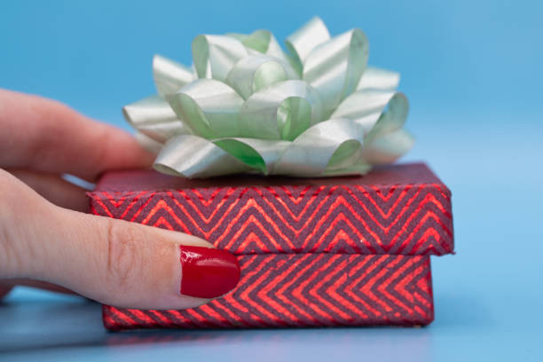 Christmas gift concept. Woman's hands holding a box with a gift in her hand. blue background