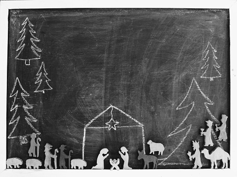 christmas holiday nativity scene on a black chalkboard with joseph mary and baby jesus and christmas trees done in chalk