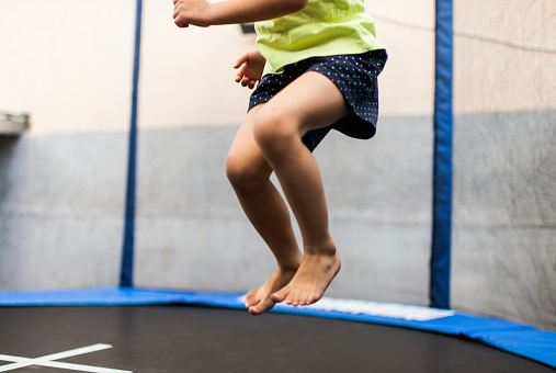 Little girl jumping on inflatable trampoline, having fun visiting amusement park during a summer vacation