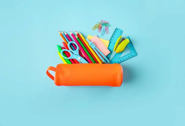 Full orange pencil case on blue background. Top view.