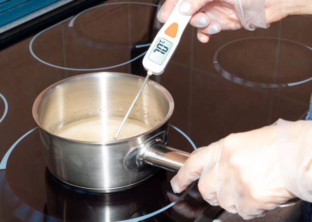 The temperature of the boiling syrup in the pan is measured with an electronic thermometer. stock photo