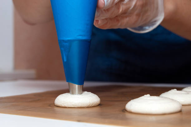 macaroons laid out on parchment from a pastry bag before baking. - fragility organization chef cake imagens e fotografias de stock