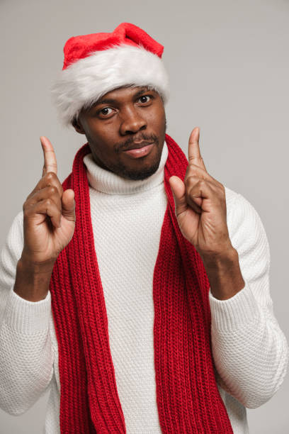 istock A young dark-skinned man in a woolen sweater, christmas hat and bright red scarf 1284246021