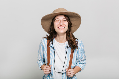 Studio portrait of a beautiful happy young Caucasian woman posing in a studio, smiling and wearing a sun hat