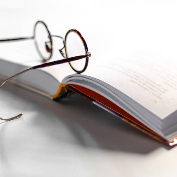 istock Old round reading glasses lie on an open book ready to read. The cozy concept 1284247122