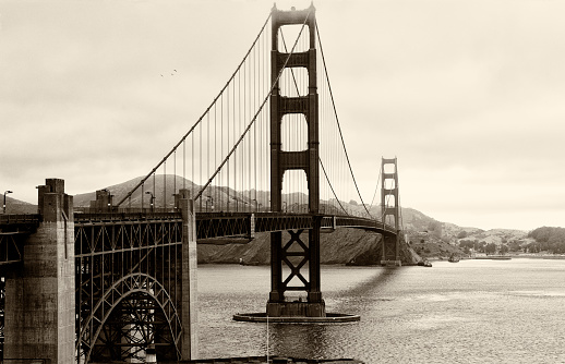 Black and white Golden Gate Bridge with boats passing underneath and San francisco in the background