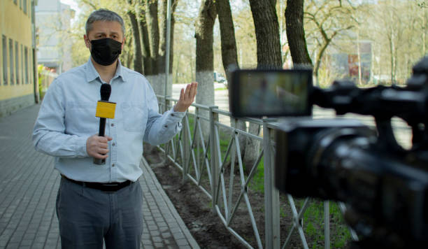 A middle- aged European journalist in a protective medical mask is reporting in a deserted city. stock photo