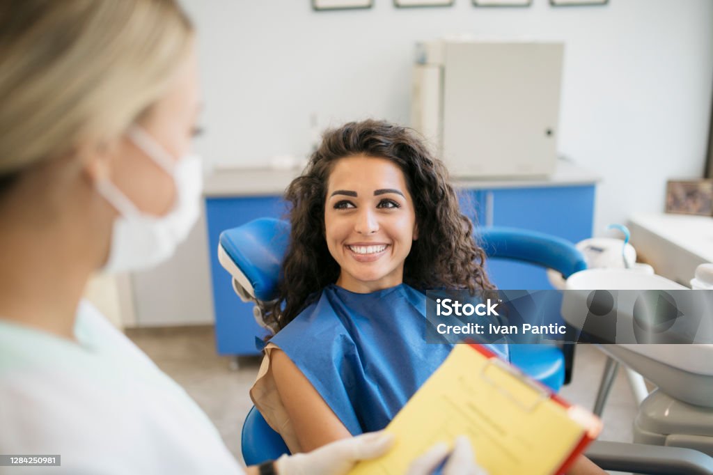 Attraktive junge kaukasische Frau im Gespräch mit ihrem Zahnarzt - Lizenzfrei Zahnarzt Stock-Foto
