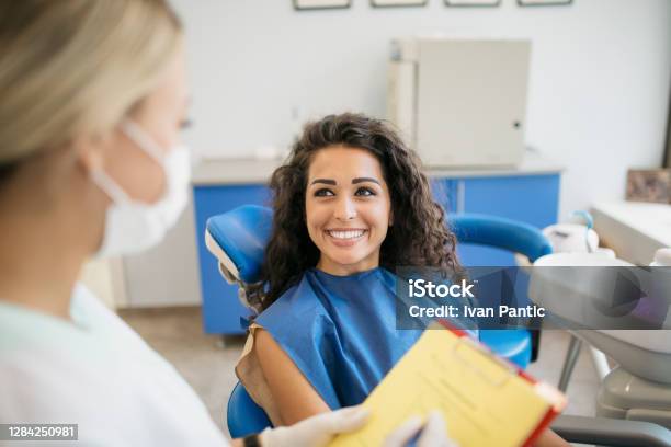 Attractive Young Caucasian Woman Talking To Her Dentist Stock Photo - Download Image Now