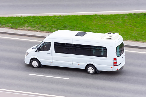 White minibus goes on the city highway street