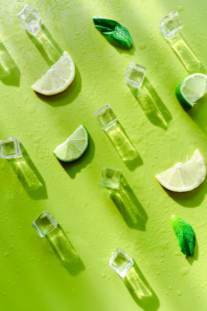 istock Fresh mint leaf and ice cubes with droplets and lime on green background 1284253346
