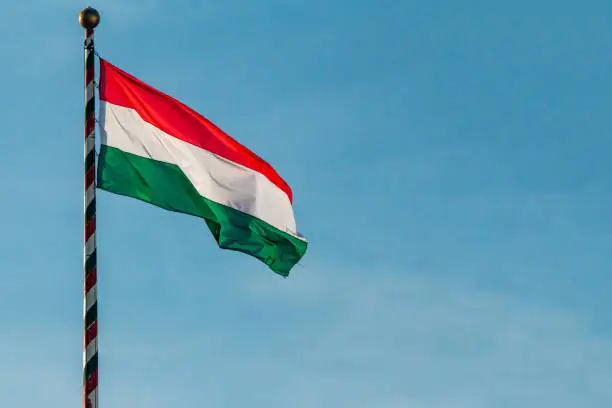 Hungary, Hungarian national flag waving on blue sky background