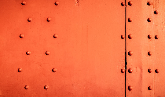 A close-up of a detail of San Francisco's Golden Gate Bridge, with patterns of rivets holding plates of one of the bridge's towers together.