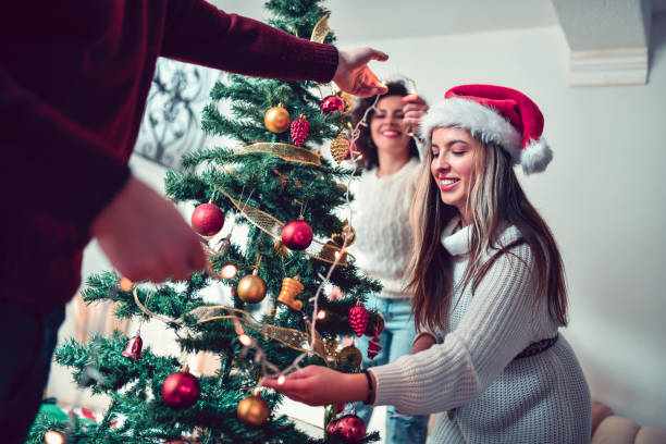 istock Friends Help Each Other To Put Lights On Christmas Tree 1284262464