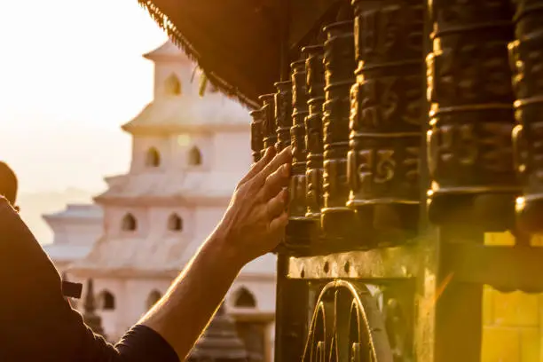 Close-up of hand turning tibetan prayer wheels at Swayambhunath Temple or Monkey Temple, Kathmandu, Nepal