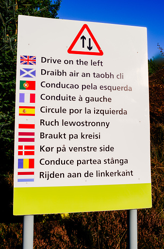 Road sign in ten different languages reminding drivers to drive on the correct side of the road.