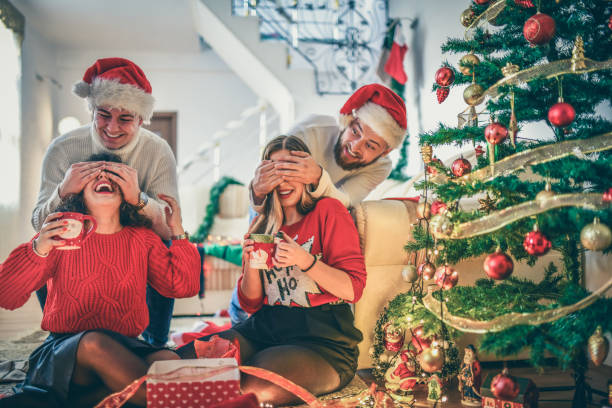 istock Males Surprising Girlfriends Drinking Tea Under Christmas Tree With Gifts 1284263753
