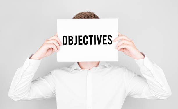 istock Man covers his face with a white paper with text Objectives 1284267954