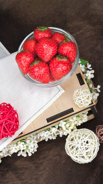 fraise douce fraîche avec la serviette blanche, fleurs de lilas et boules de rotin sur le fond en bois. composition de flatlay d’été, orientation verticale - doily freshness raw sweet food photos et images de collection