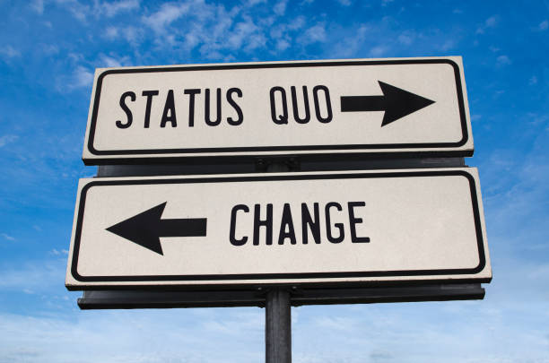 Status quo vs change. White two street signs with arrow on metal pole with word. Directional road. Crossroads Road Sign, Two Arrow. Blue sky background. Status quo vs change. White two street signs with arrow on metal pole with word. Directional road. Crossroads Road Sign, Two Arrow. Blue sky background. adapting stock pictures, royalty-free photos & images