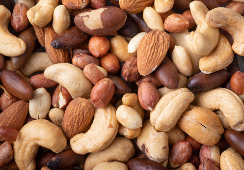 Closeup top view of mixed nuts over a wooden background. Peanuts, brazilian nuts, cashew, baru and almonds.