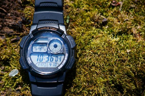 istock Hand-held clock on a wooden background covered with moss. 1284272281