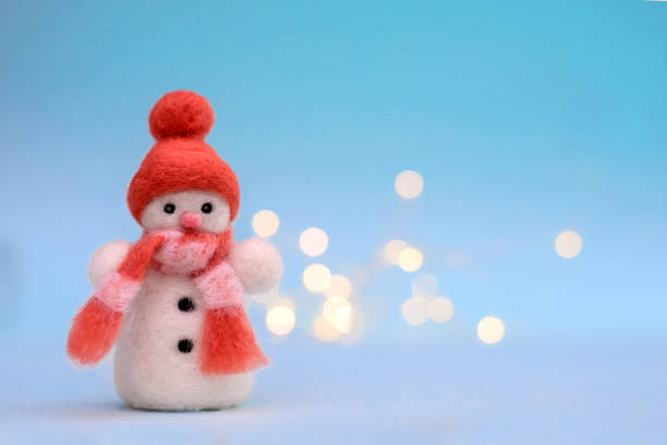 istock Toy wool snowman on a blue background with bokeh 1284272469