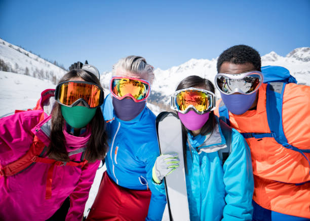 gruppo felice di amici che sciano e indossano maschere facciali durante la pandemia - snowboarding friendship snow winter foto e immagini stock