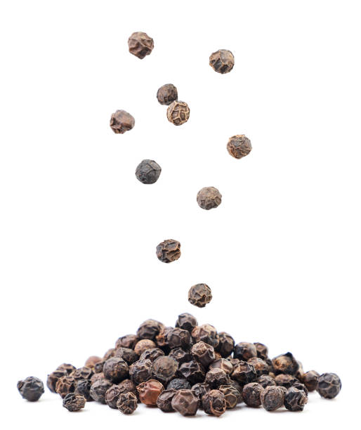 black peppercorns falling on a pile on a white background. isolated - pepper imagens e fotografias de stock