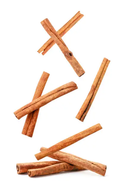 Photo of Cinnamon sticks fly and fall on a heap on a white background. Isolated