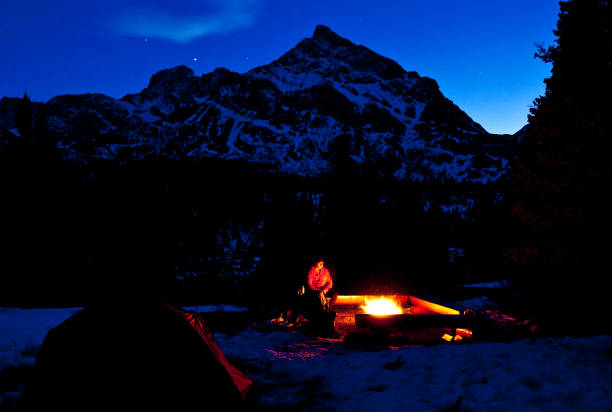 istock Winter Camping In Mountains With Caucasian Man Standing By Fire 1284277738