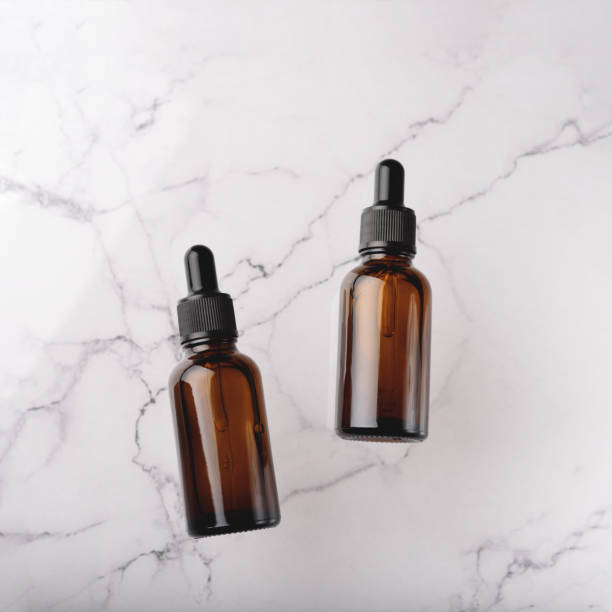 istock Glass dropper bottles on the white marble background. 1284277851