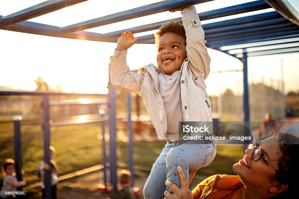You can do it Kid playing with mother in public park Child Stock Photo