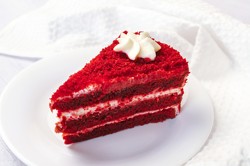 Red Velvet Cake sliced in piece on white plate on white background for celebrate X'mas season or Valentines day. Or for bakery online delivery.