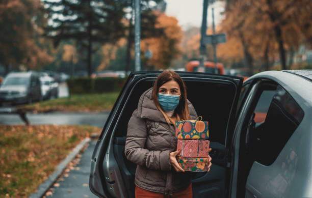 istock A young woman wears a protective mask while packing presents into car 1284282838