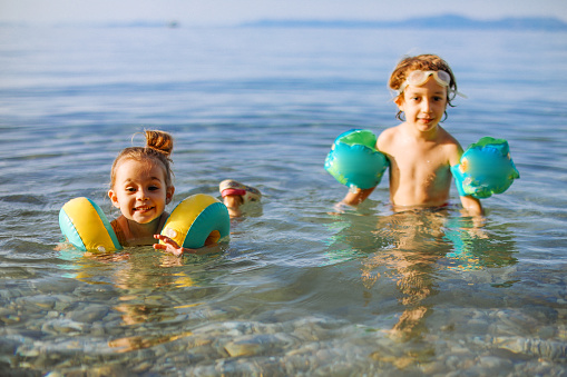 Group of Diversity little child boy and girl friends playing in the ocean at tropical beach together on summer vacation. Happy children kids enjoy and fun outdoor lifestyle travel ocean on beach holiday.