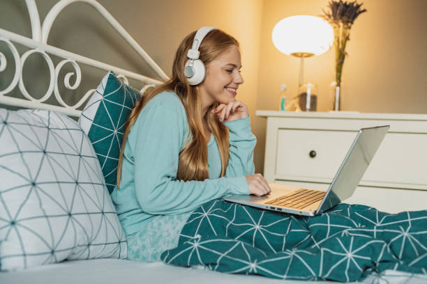 istock Young woman relaxing in bed and using laptop 1284284055