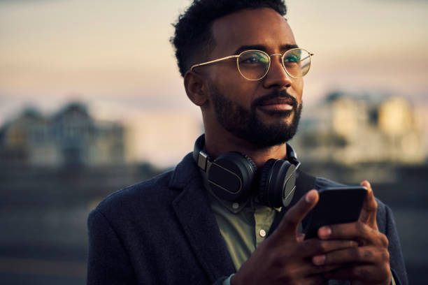 He's on a mission Cropped shot of a handsome young businessman using his cellphone while out in the city guy looking at cell phone stock pictures, royalty-free photos & images