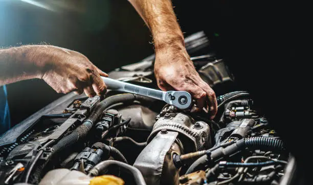 Photo of Auto mechanic working on car engine in mechanics garage. Repair service. authentic close-up shot