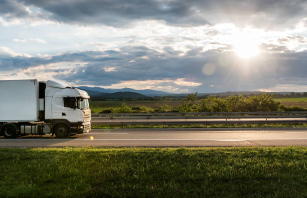 Big White truck on highway White truck is on highway - business, commercial, cargo transportation concept, beautiful sunset sky, clear and blank space - side view truck mode of transport road transportation stock pictures, royalty-free photos & images