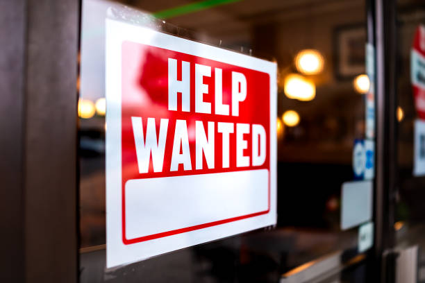 Sign text closeup for help wanted with red and white colors by entrance to store shop business building during corona virus covid 19 pandemic Sign text closeup for help wanted with red and white colors by entrance to store shop business building during corona virus covid 19 pandemic employment and labor stock pictures, royalty-free photos & images