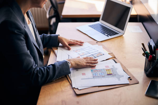istock Female architect sitting at the table with laptop and papers 1284300616