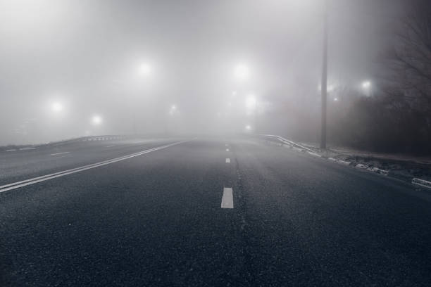 istock Foggy misty night road illuminated by street lights 1284302539