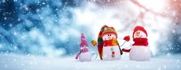 istock Little knitted snowmen on soft snow on blue background 1284304664