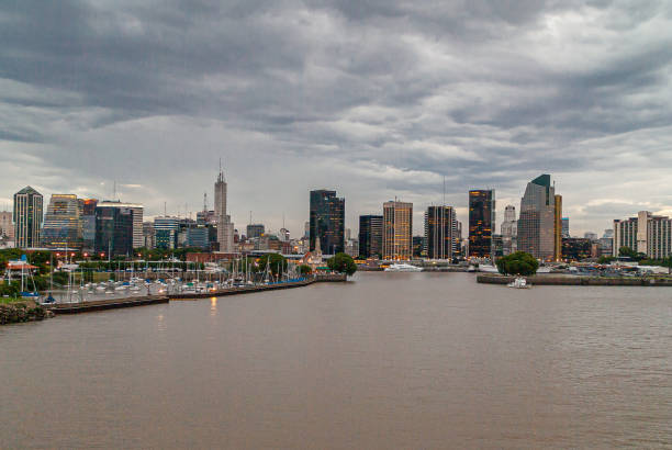 Buenos Aires, Argentina- December 19, 2008: Sunset over east side skyline at harbor shows string of high rise office buildings under gray cloudscape. Light galore and yacht harbor up front.