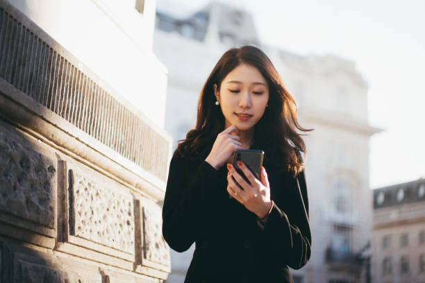 istock Asian businesswoman walking on the street using her smartphone for communicating 1284309607