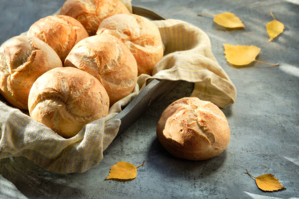 istock Kaiser, or Vienna buns in bread basket on dark rustic background with yellow Autumn leaves 1284310538