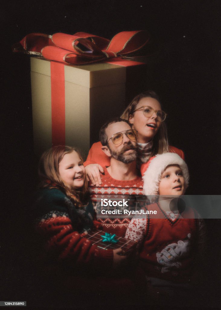Funny Vintage Styled Family Ugly Christmas Sweater Portrait An awkward retro styled image of a family getting a studio portrait for the holiday season, wearing ugly Christmas sweaters and daydreaming of their gifts. Family Stock Photo