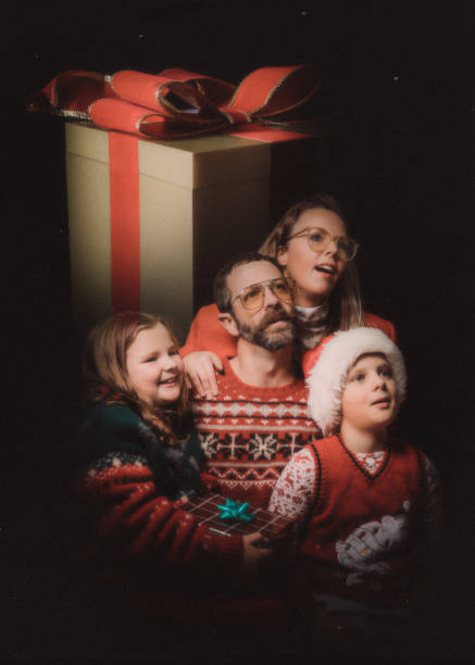 Funny Vintage Styled Family Ugly Christmas Sweater Portrait An awkward retro styled image of a family getting a studio portrait for the holiday season, wearing ugly Christmas sweaters and daydreaming of their gifts. ugliness photos stock pictures, royalty-free photos & images